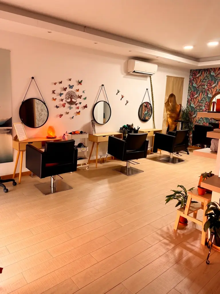 Sala de peluquería del Salón Raíz y Alma, con espejos redondos y mariposas en la pared