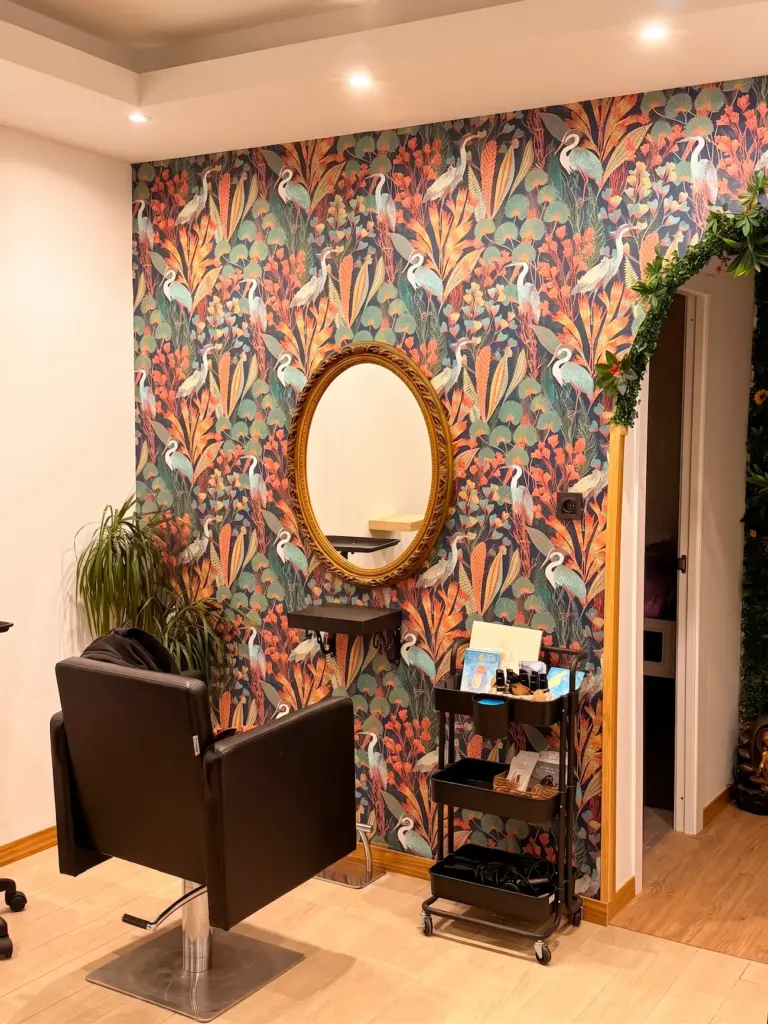 Rincón de peinado del Salón Raíz y Alma, con papel pintado de garzas y espejo dorado
